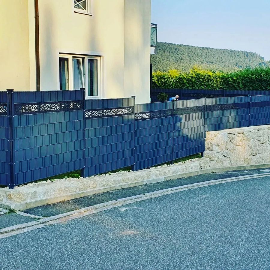 Doppelstabmattenzaun mit eingezogenen blauen Sichtschutzstreifen auf einer Mauer