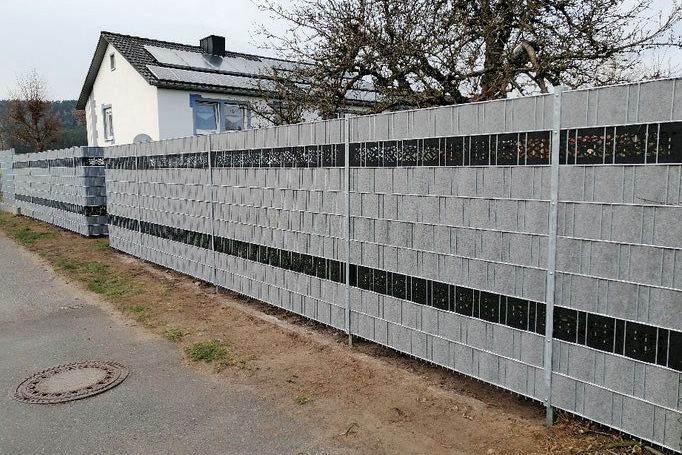 Lange Zaunanlage aus Doppelstabmatten mit hellen Sichtschutzstreifen entlang einer Straße