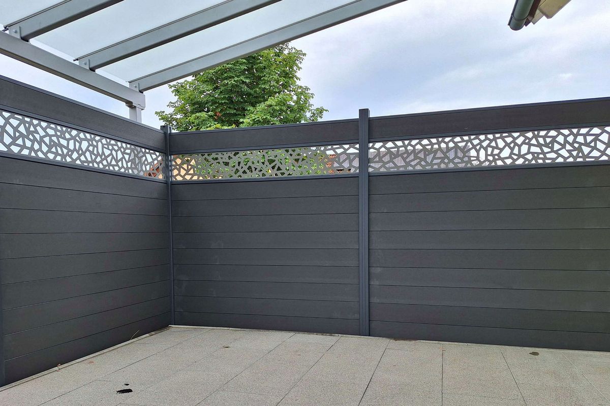Terrassenüberdachung mit Glasdach und anthrazitfarbenem WPC-Sichtschutz mit Ornament-Blende