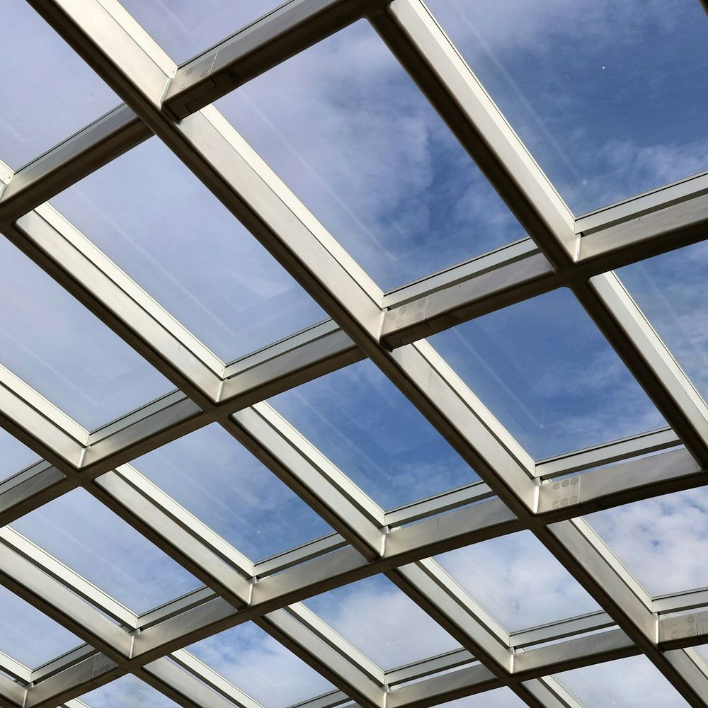 Blick von unten durch ein Glasdach einer Terrassenüberdachung in den Himmel